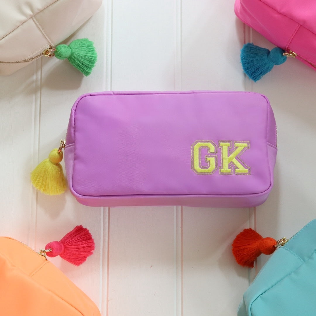 Personalised lilac nylon pouch bag with varsity style initials embroidered on in yellow with a matching yellow tassel zipper pull. Custom travel clutch handbag for cosmetics, toiletries or everyday essential - perfect gift for her.