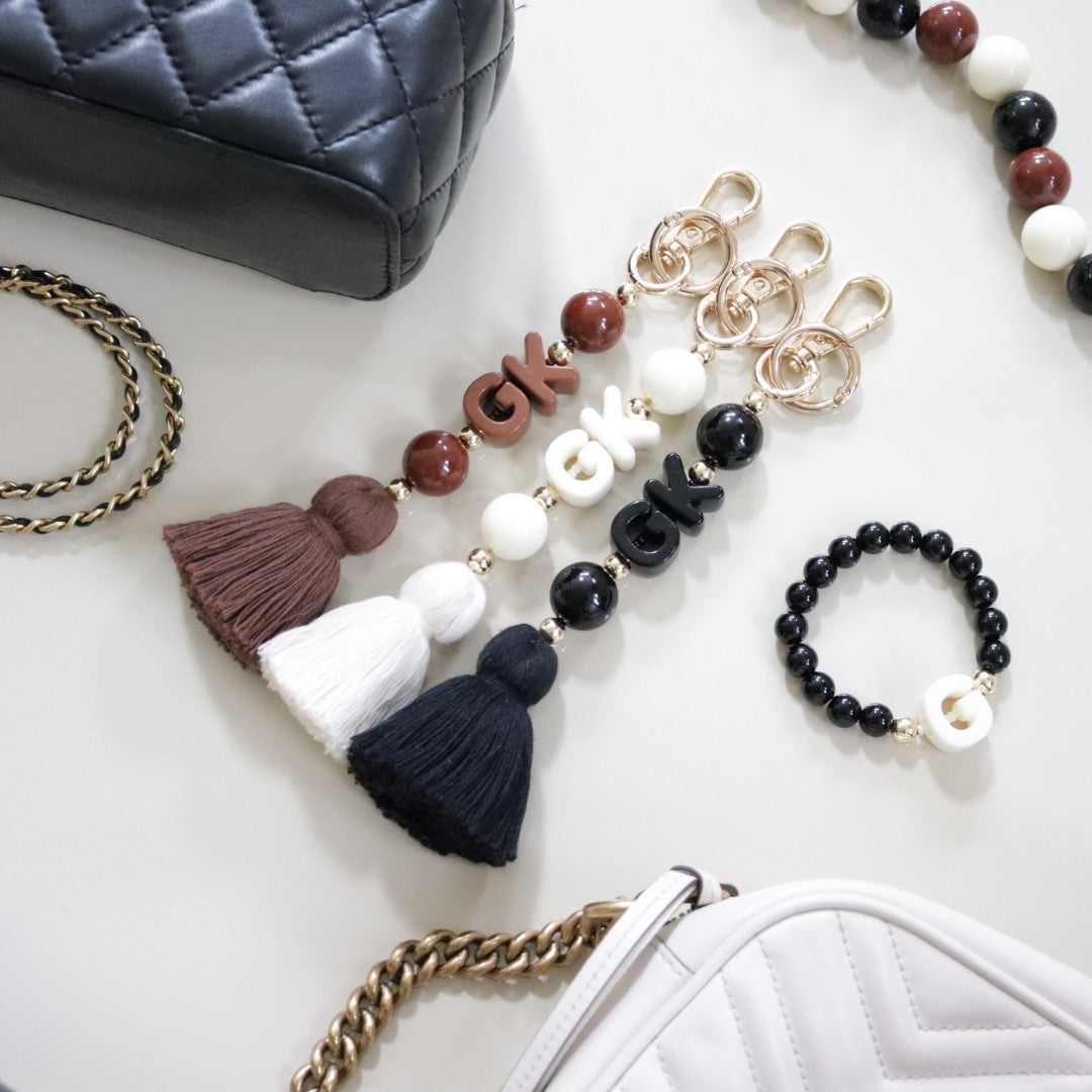 Personalised beaded keychain or bag charm in a choice of brown, cream or black with gold accents, chunky bead custom initials & matching colour tassel. Perfect gift for her.