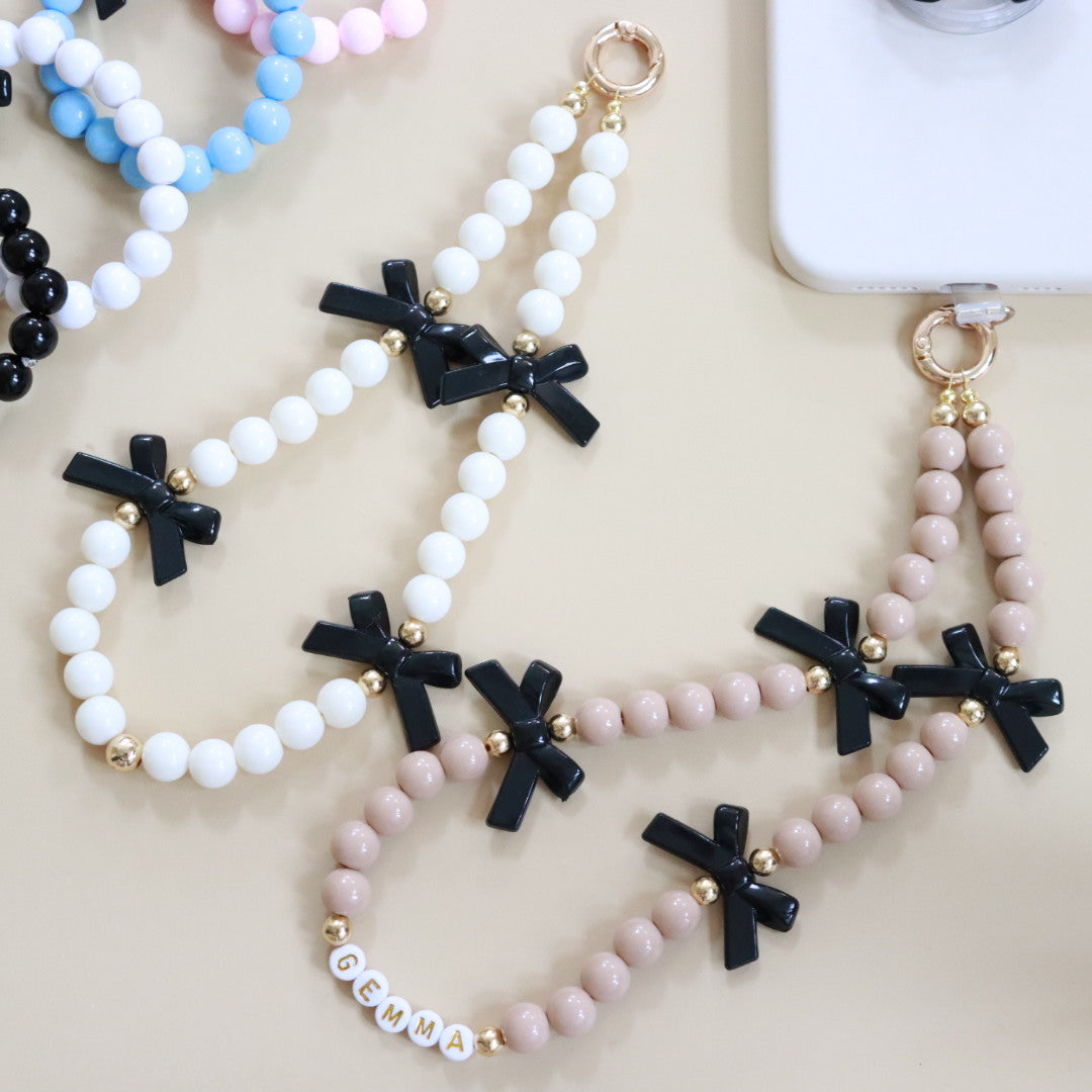 Beaded phone wristlet charm with custom name beads, cute black bows, round acrylic & gold spacer beads. Handmade phone strap, the perfect gift for girls, teens & adults.