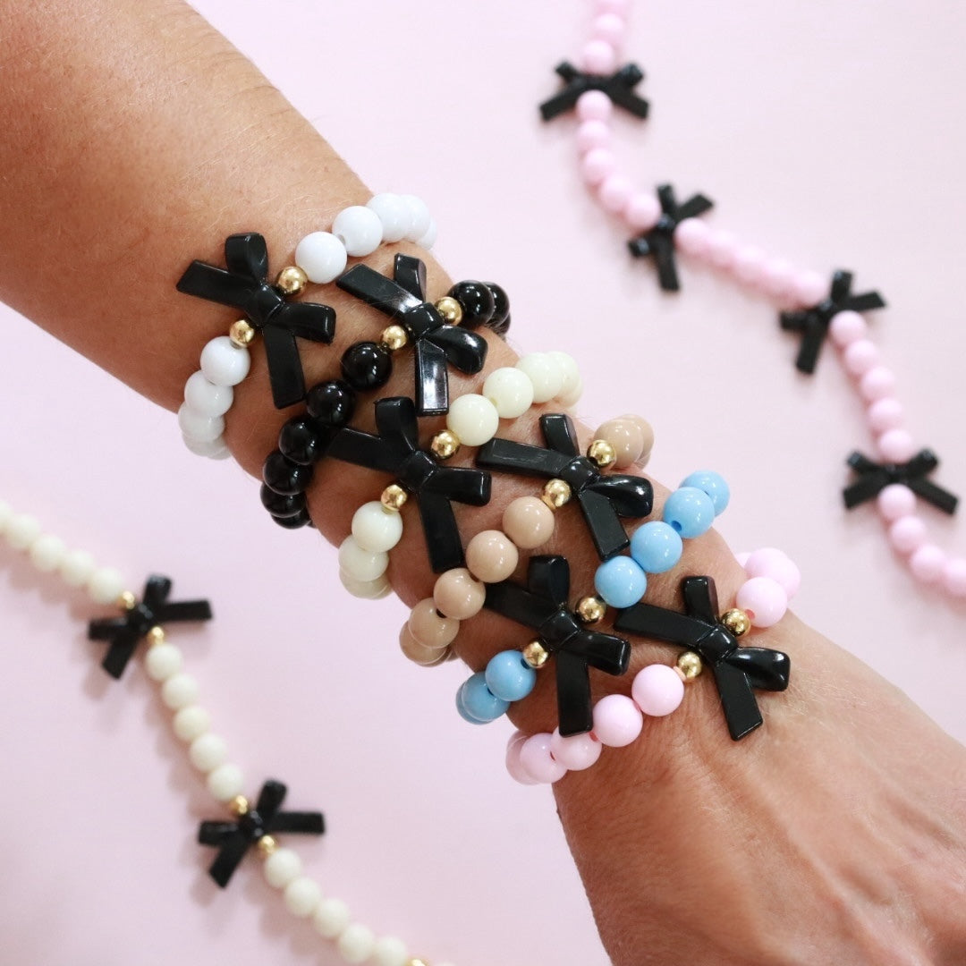 Beaded bracelet in a choice of 6 colours. Featuring a cute black bow round acrylic & gold spacer beads. Handmade stretch bracelet, the perfect gift for girls, teens & adults.