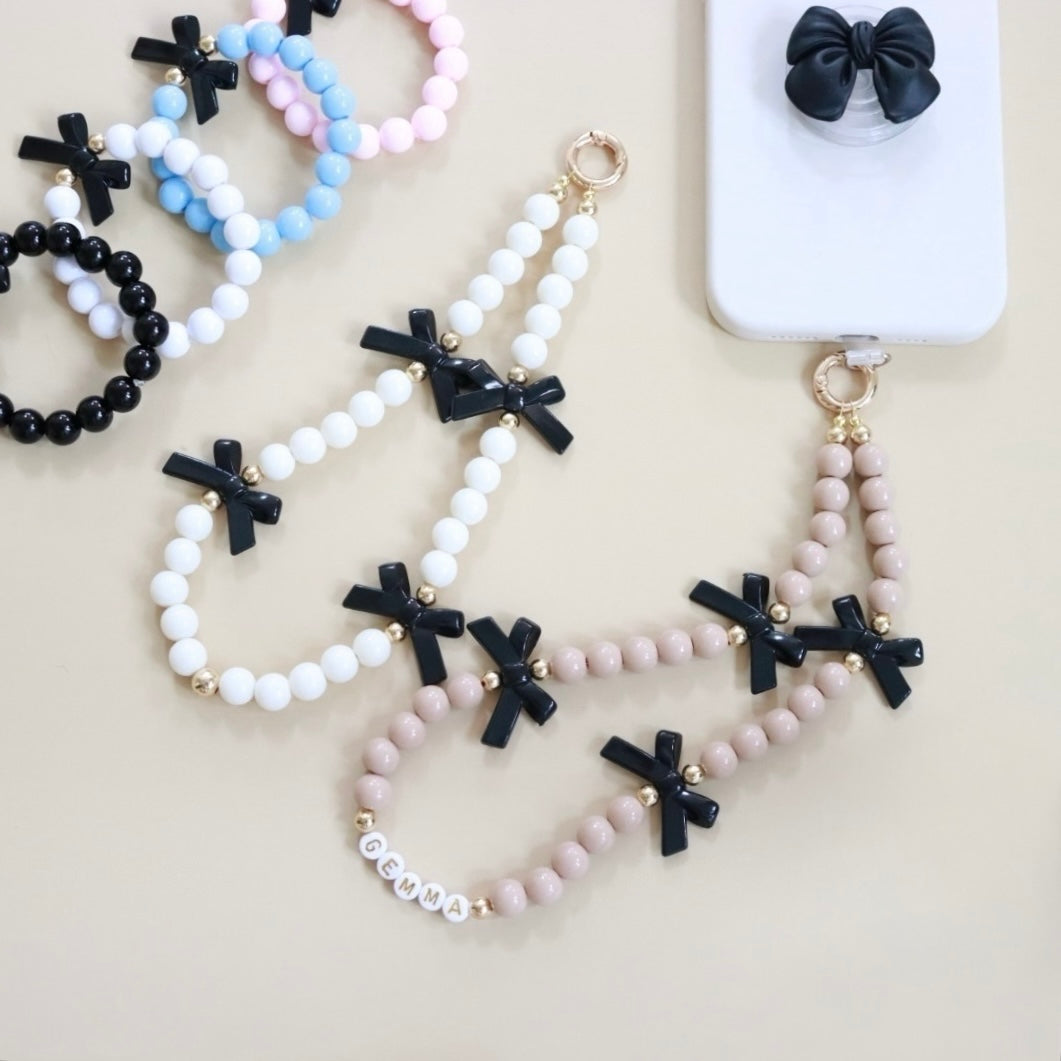 Beaded phone wristlet charm with custom name beads, cute black bows, round acrylic & gold spacer beads. Handmade phone strap, the perfect gift for girls, teens & adults.