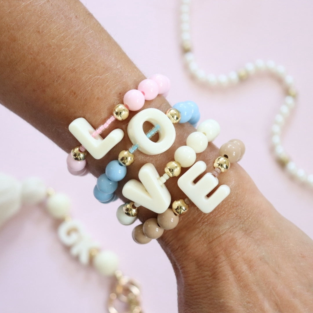 Pastel coloured beaded bracelet featuring a chunky cream initial/letter bead in the centre strung over a row of Miyuki seed beads with gold plated spacer beads either side. Personalisable handmade stretch fidget bracelet, the perfect gift for girls, teens & adults.